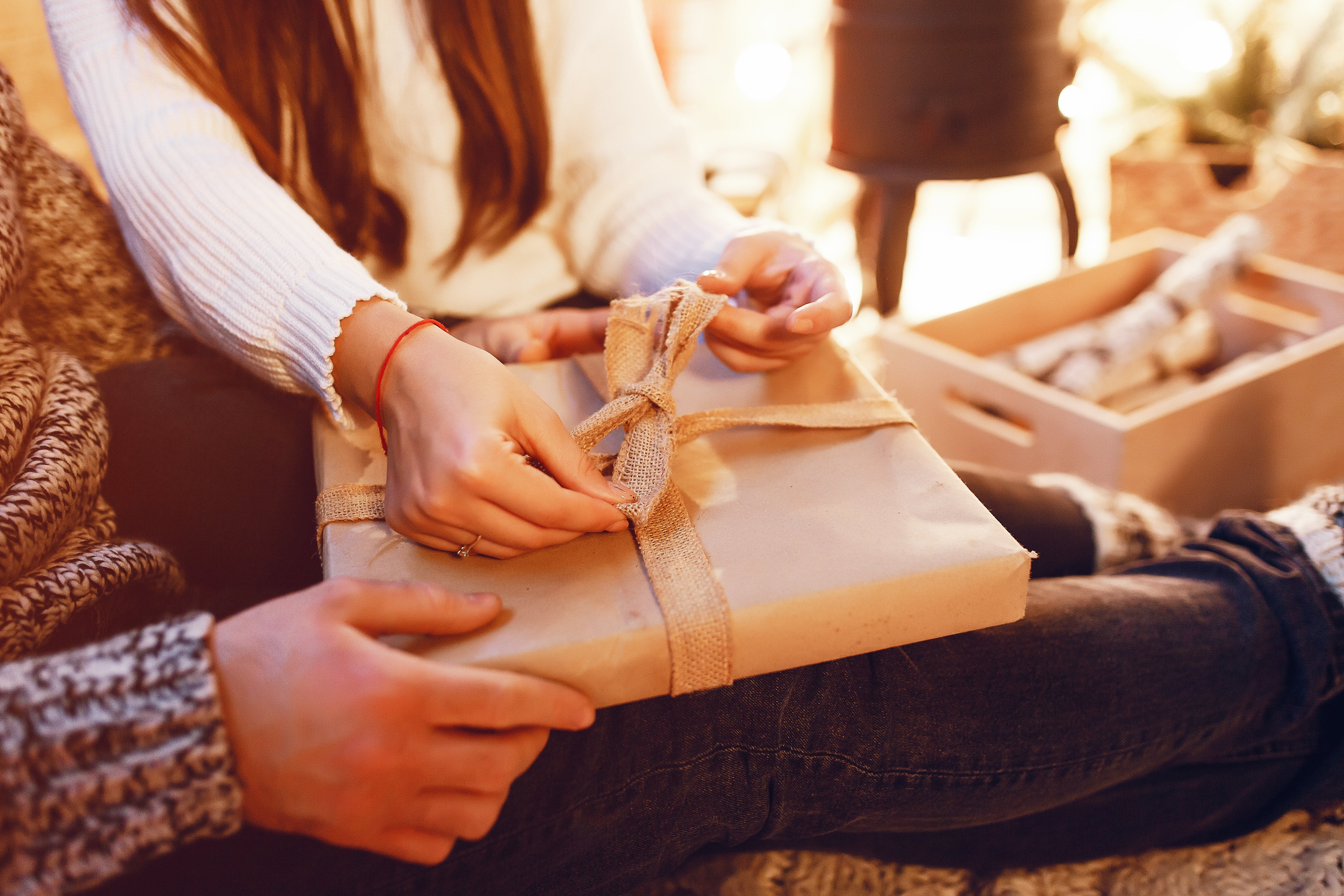 Two people holding and opening a wrapped present