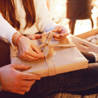 Two people holding and opening a wrapped present