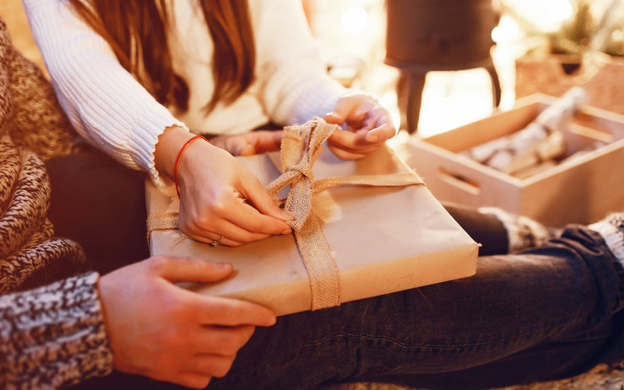 Two people holding and opening a wrapped present