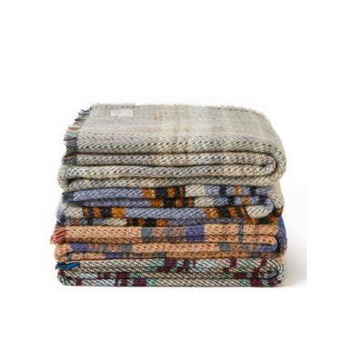 A stack of Tweedmill Recycled All Wool Throws of Various Colours, by Tweedmill Textiles, stacked on top of each other.